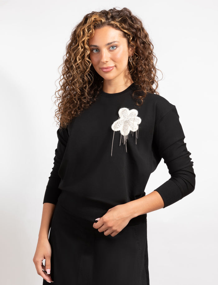 Black long-sleeve top, crew neck, white floral applique with hanging strands