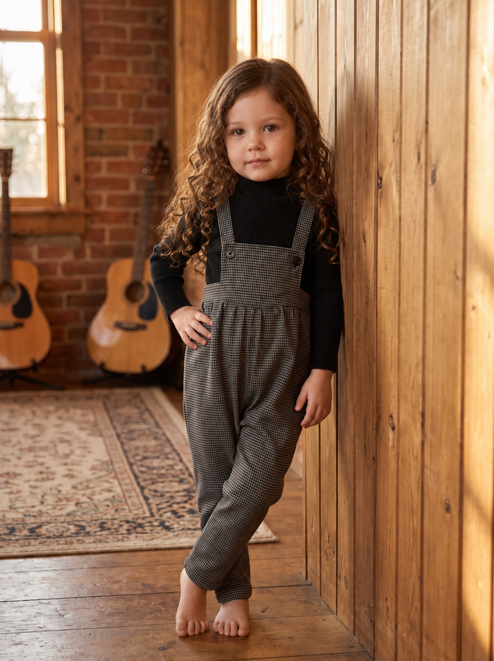 Black tweed suspender romper with adjustable buttons.