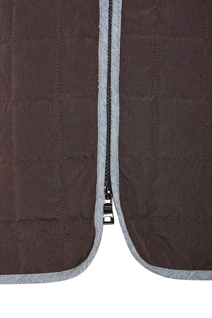 Close-up of a brown quilted jacket with a zipper detail on a white background