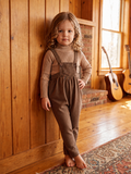 Brown tweed suspender romper with adjustable buttons.