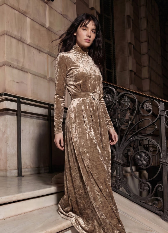 Beige crushed velvet long sleeve maxi dress with mock turtle neck collar and metal loop self belt.