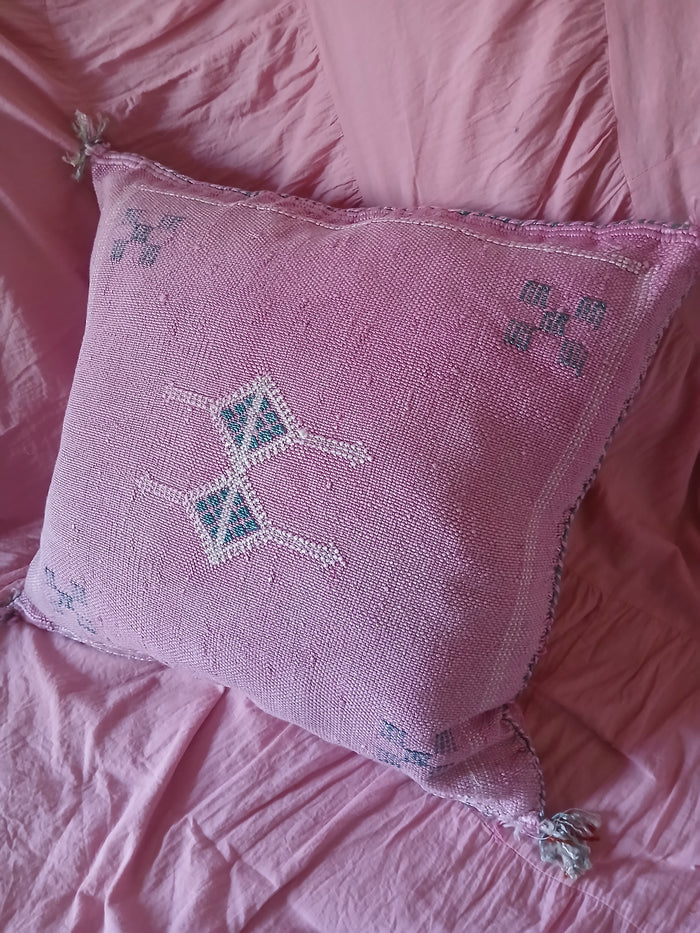 Pink embroidered pillow on a matching pink fabric background