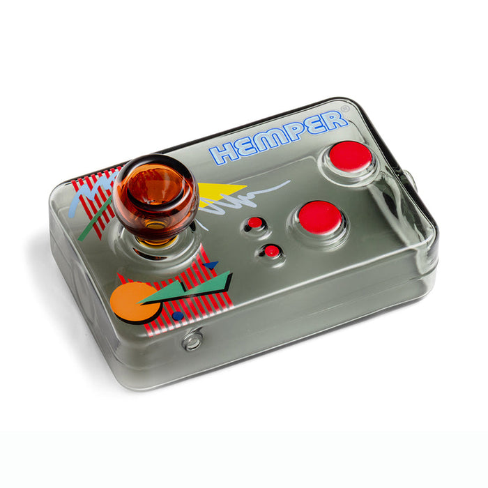 Angled overhead shot of Hemper arcade controller glass hand pipe showing amber joystick bowl, red buttons, and 80s-style graphics.