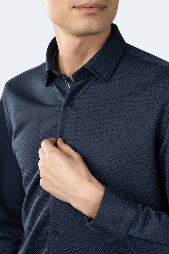 Man wearing a dark blue patterned shirt against a light background