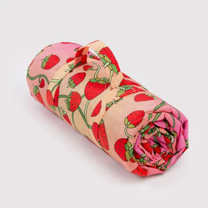 Rolled-up nylon blanket with strawberry pattern on a light gray background