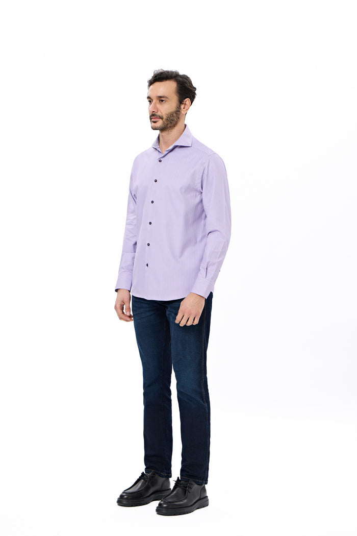 Man wearing a light purple shirt and dark jeans on a white background