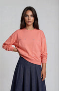 Peach sweatshirt top with grommet pockets and midriff waist.