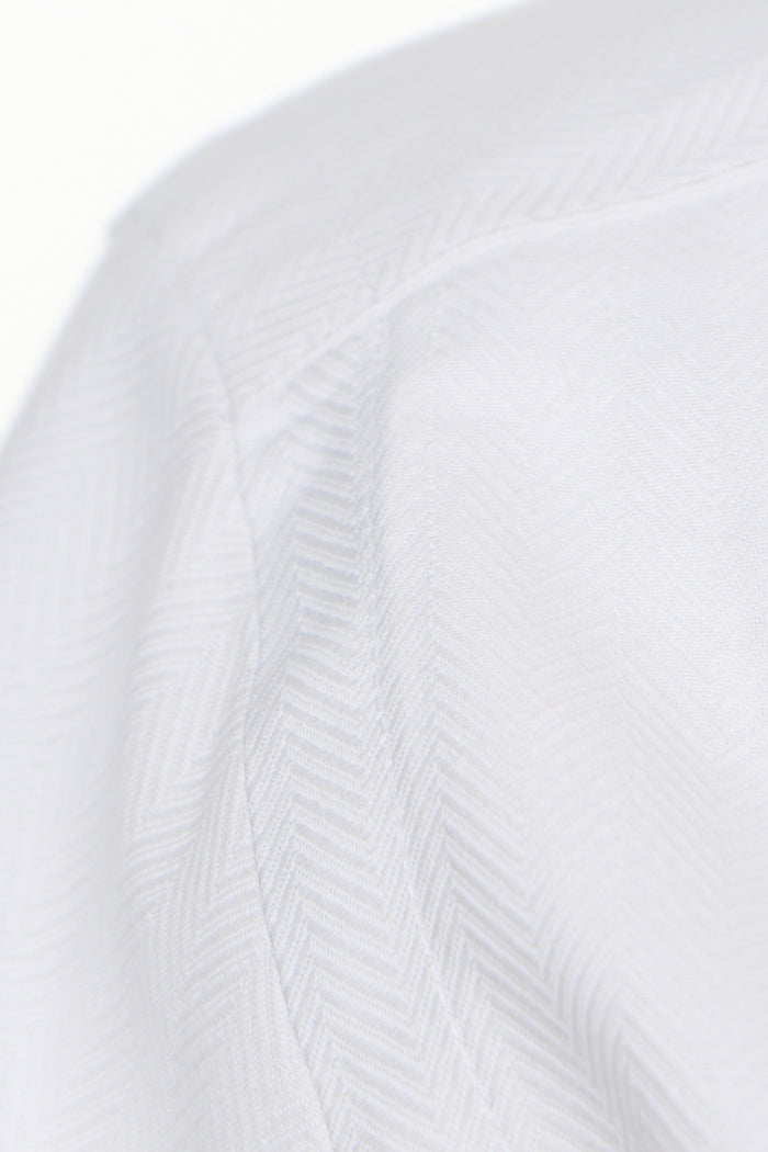 Close-up of a textured white fabric with a subtle pattern on a white background